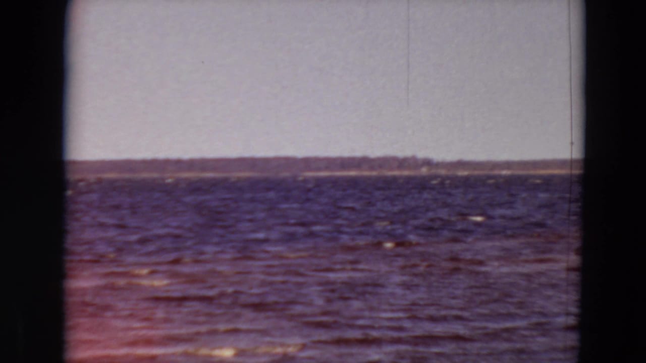 Rippling water with a distant shore across the horizon.