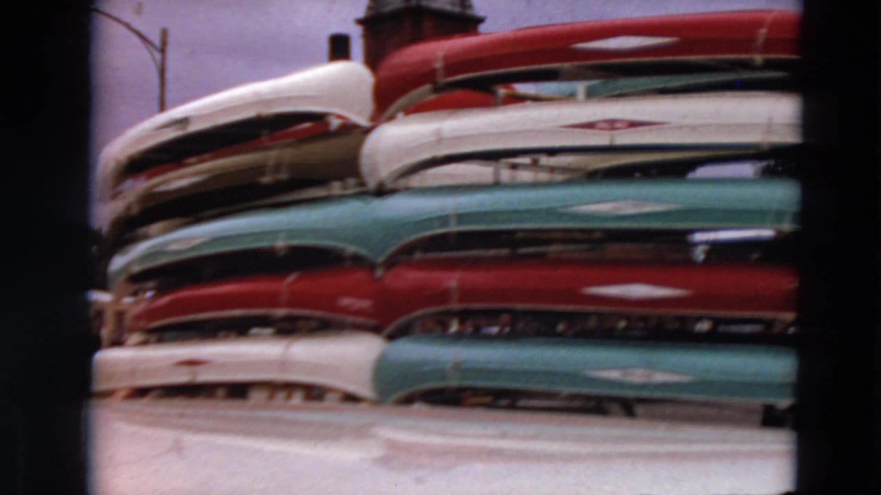 Closer view of stacked canoes with red, white, and teal hulls.