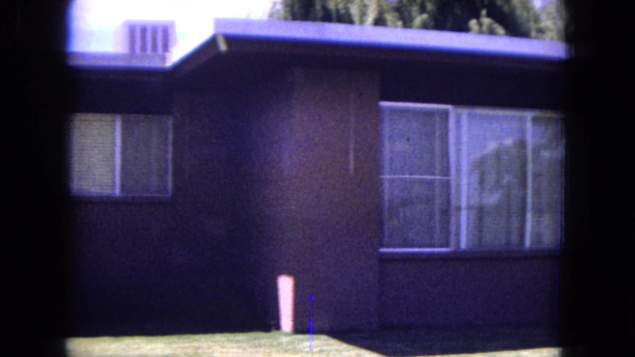 1970 White Sands, Florida frame of the same suburban house exterior, with shaded siding, bright lawn, and large curtained windows.