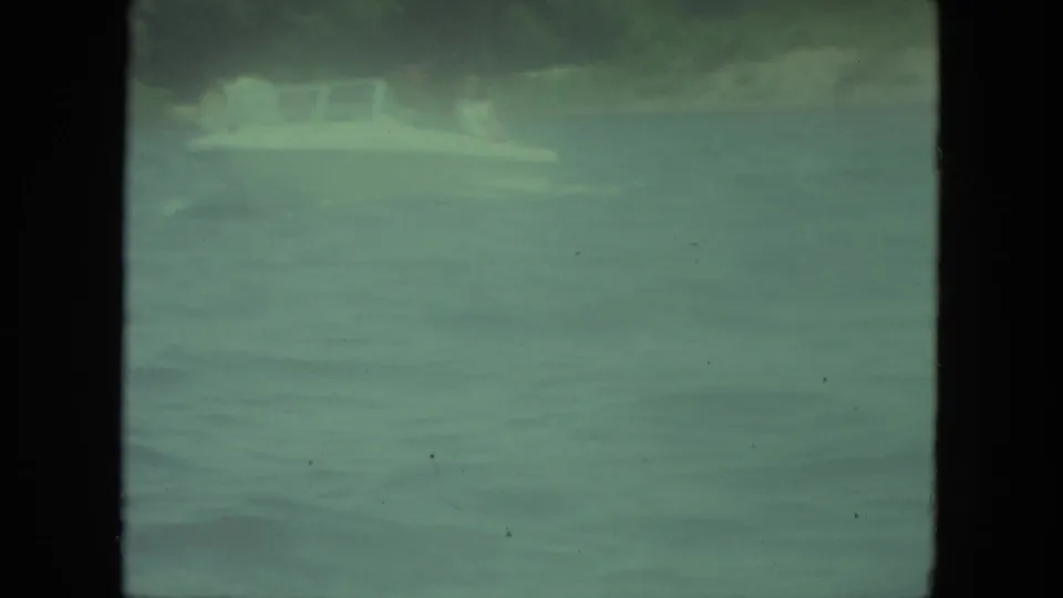 1971 Mississippi-labeled 8mm frame showing a small white boat on calm water with a dark shoreline beyond.