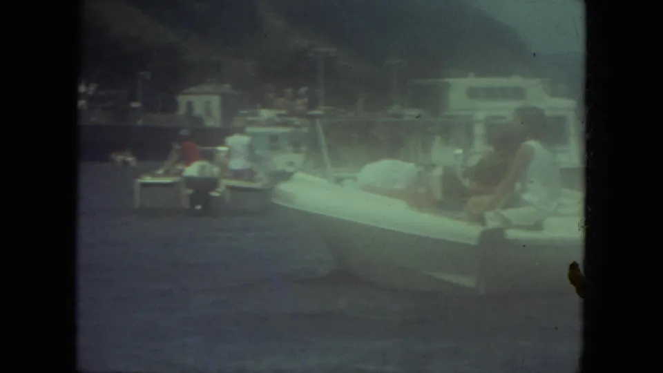 1971 Mississippi-labeled 8mm frame showing seated people in a small white boat near other boats and a shoreline.