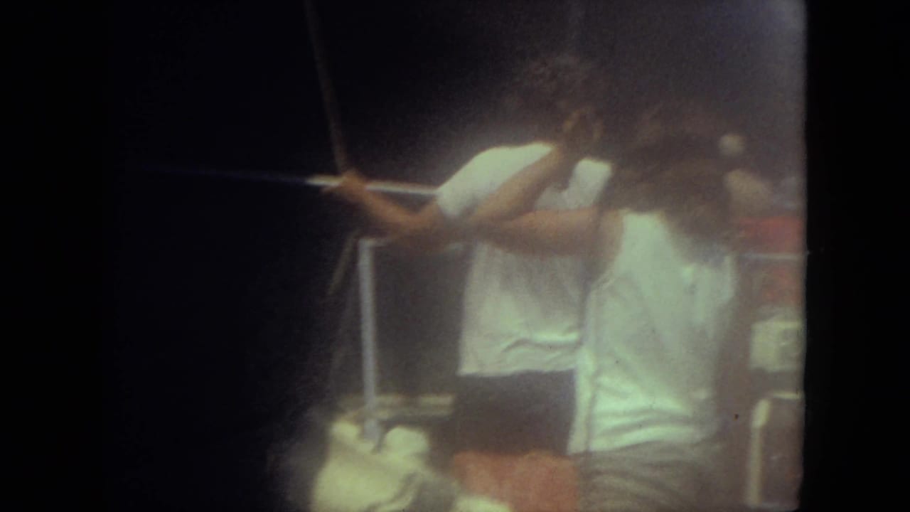 1971 Mississippi home-movie frame showing people aboard a small boat, one standing near a rope or rail in soft 8mm focus.