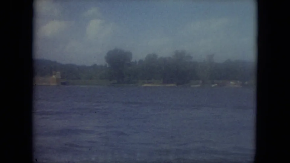 1971 Mississippi 8mm frame showing lake water, far shoreline trees, low hills, and hazy sky before the boat enters view.