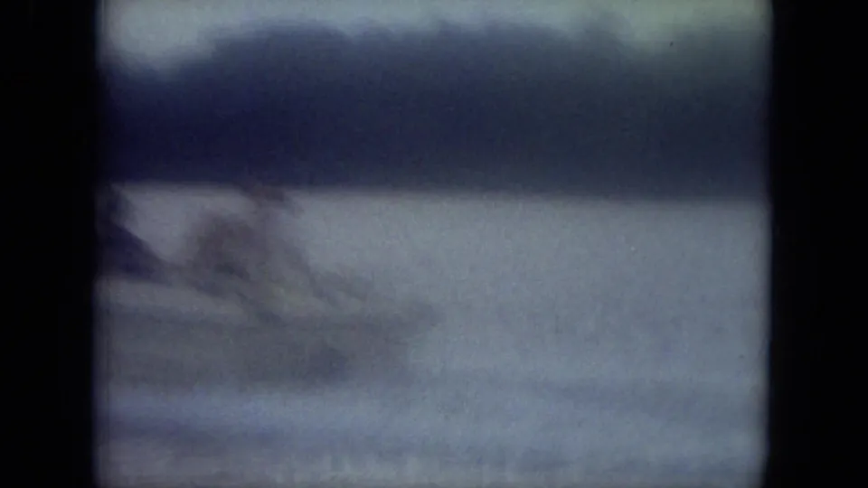 Soft 8mm frame from the Mississippi boat ride showing blurred water movement, wake, and a dark tree line in the distance.