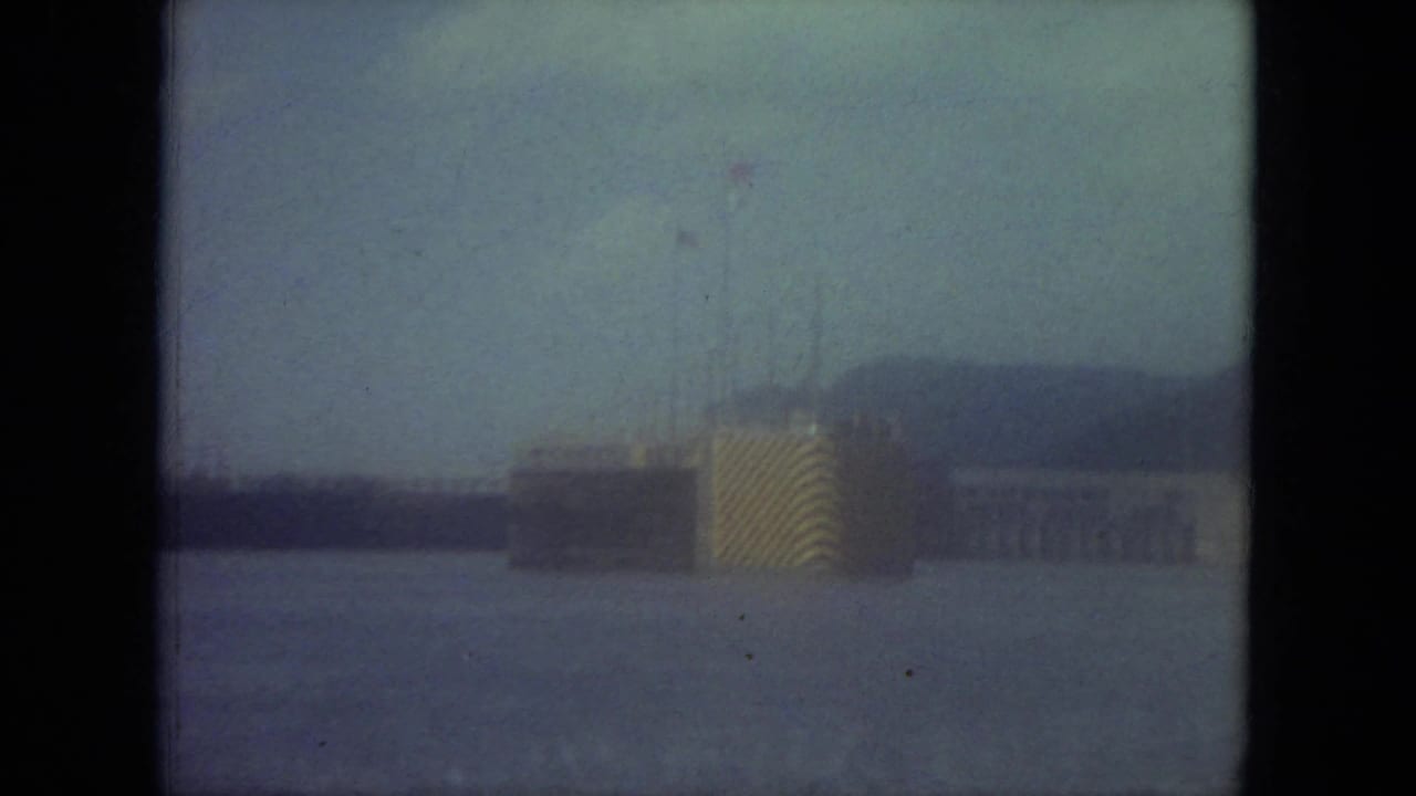 Hazy waterfront view with a large ship or structure across open water.