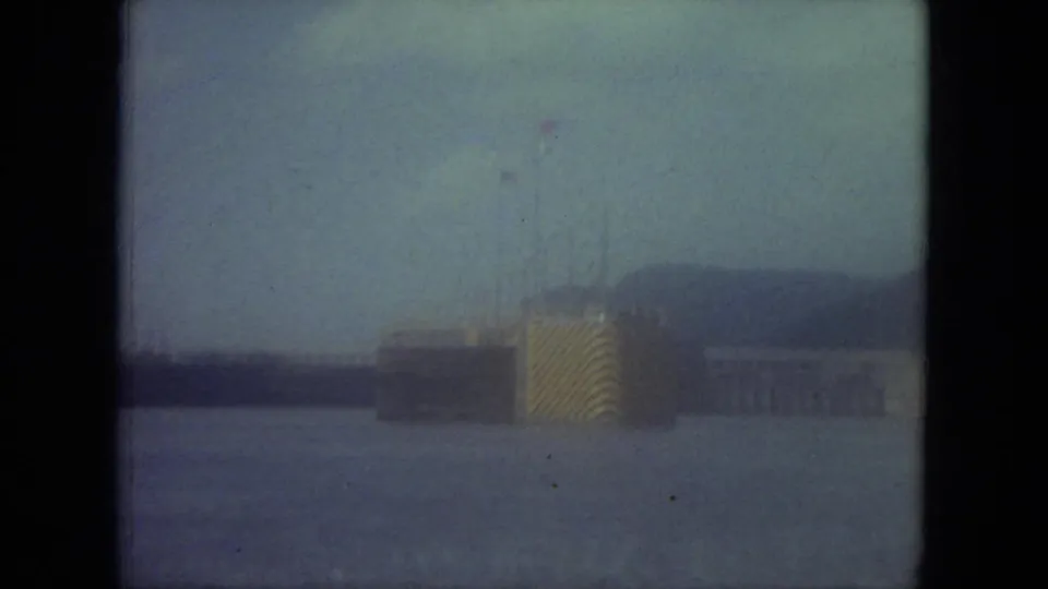 Soft 1971 Mississippi home-movie frame showing open water and a hazy ship or waterfront structure in the distance.