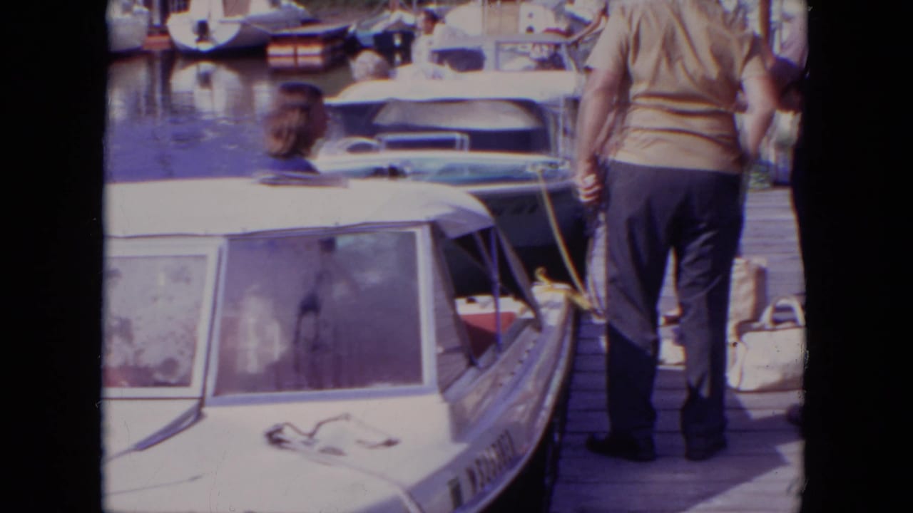 1971 Mississippi marina view with a man walking on the dock beside covered small boats and calm water.