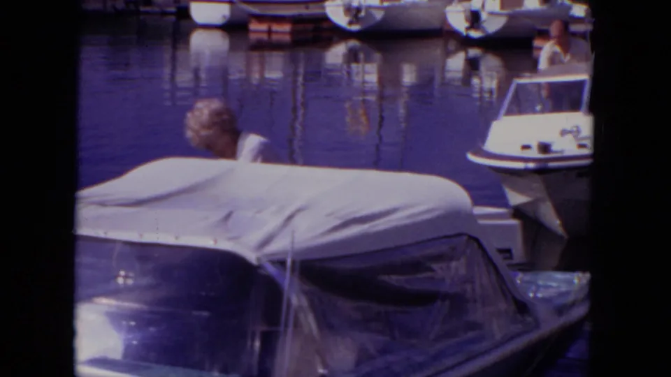 1971 Mississippi home-movie frame showing a covered motorboat in the foreground with other marina boats behind it.