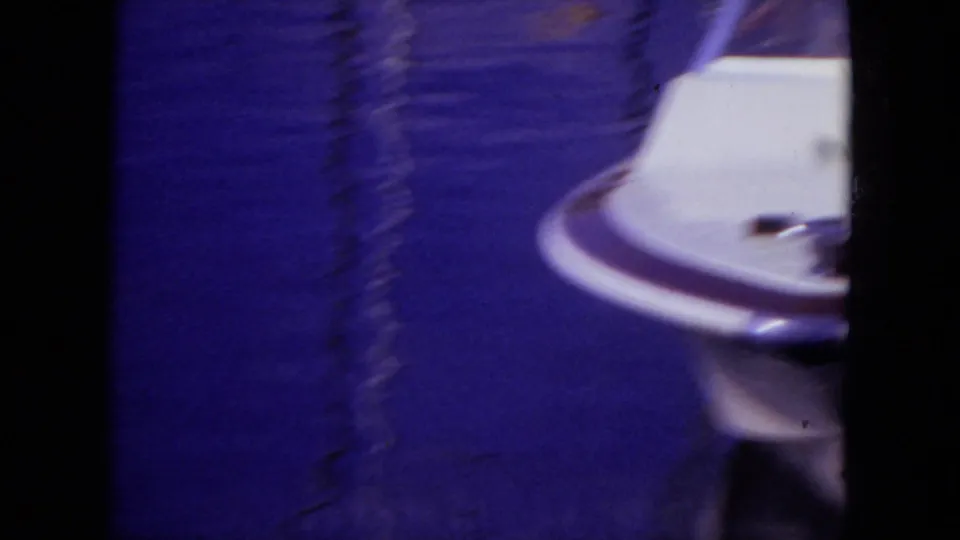 A soft, motion-blurred 1971 Mississippi 8mm frame shows part of a white speed boat moving across blue lake water.