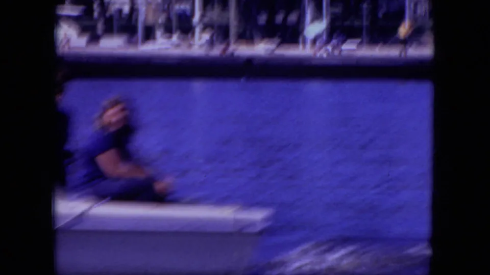 A young person in dark clothing sits on the rear of a white boat on a Mississippi lake, with shoreline details in the distance.