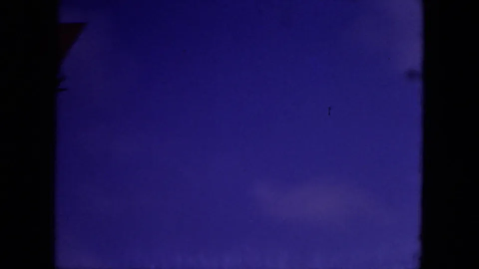 Dark blue underexposed 8mm frame with only a partial edge shape visible, likely between clearer boat or sky shots.