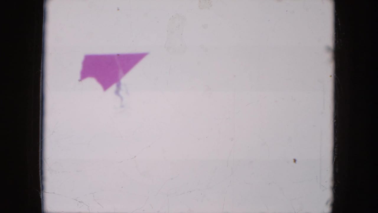 Red hang glider wing near the top of a pale sky frame.