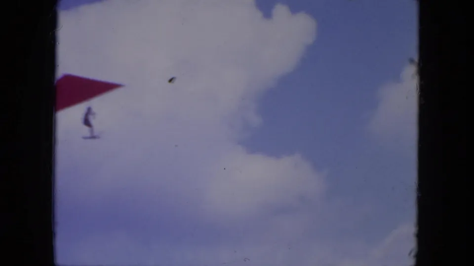 The red wing and small pilot silhouette are visible against blue sky and white clouds in the 1971 Mississippi 8mm clip.