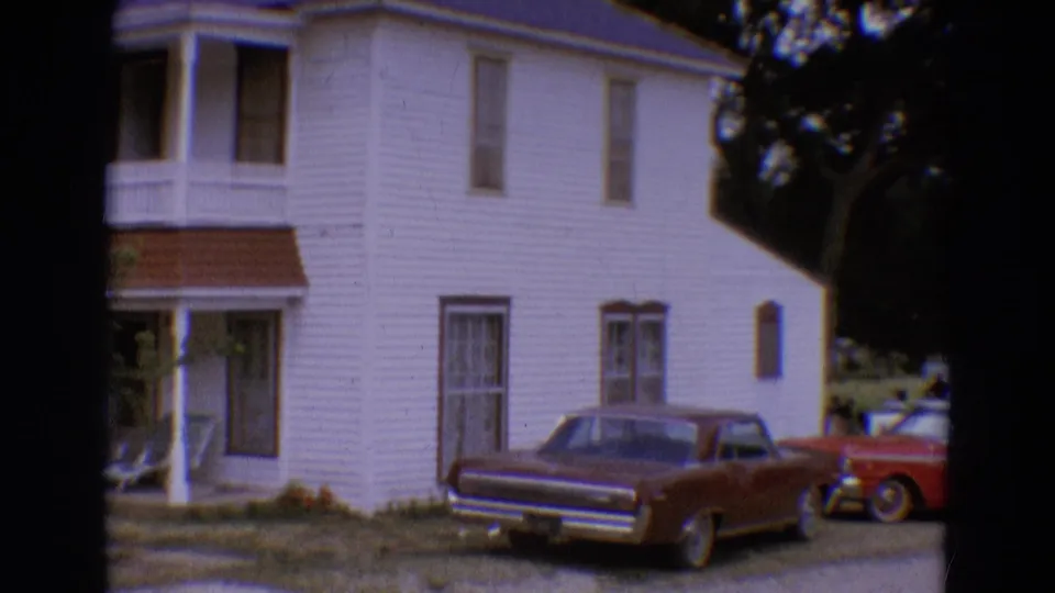 The camera pan reveals more of the house exterior, a maroon sedan, and part of a red classic car in Diller, Nebraska.