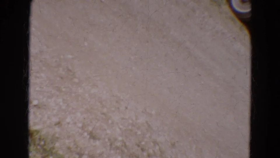 Ground-facing 8mm frame from the Diller, Nebraska clip, showing pale surface texture, gate edge, and film wear.