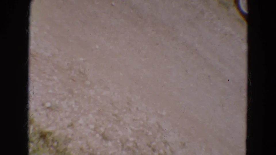 1968 Diller, Nebraska home-movie frame showing a blurred ground surface with dark 8mm gate borders and scratches.