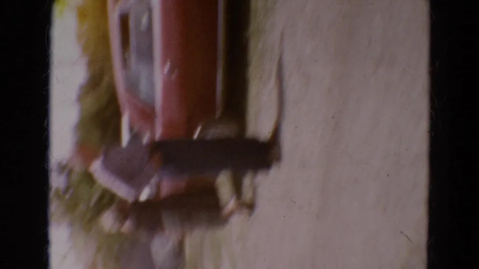 Shaky 1968 Diller, Nebraska 8mm frame with a blurred reddish car-like form and pale ground during rapid camera movement.