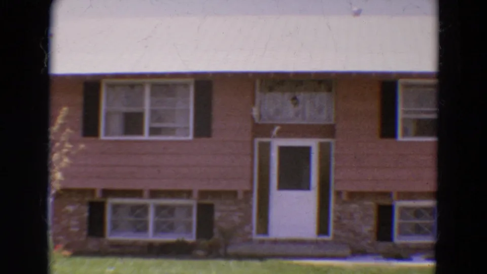 1968 Diller, Nebraska home exterior with the white door and multiple shuttered windows framed tightly in soft 8mm footage.