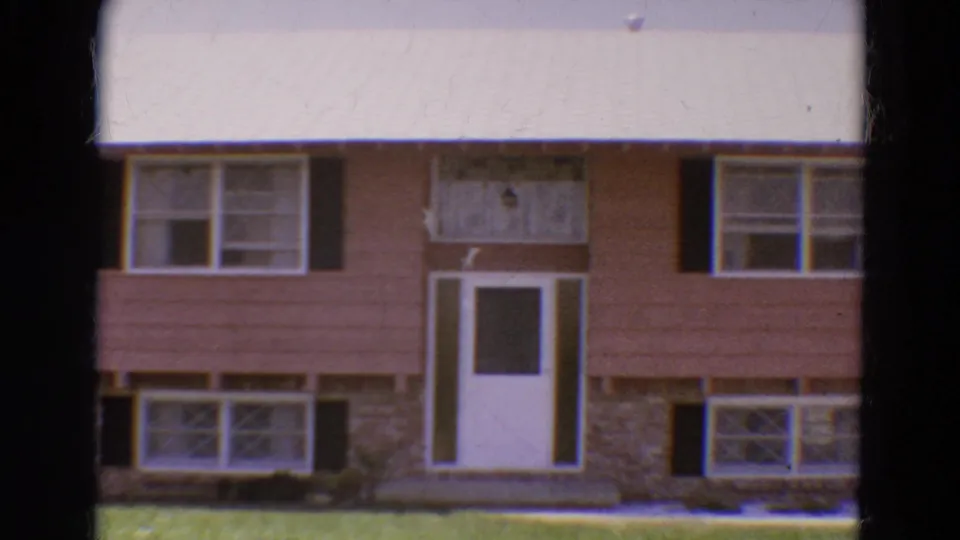 1968 Diller, Nebraska frame showing the front of a modest split-level house with a white door, brick base, black shutters, and lawn.