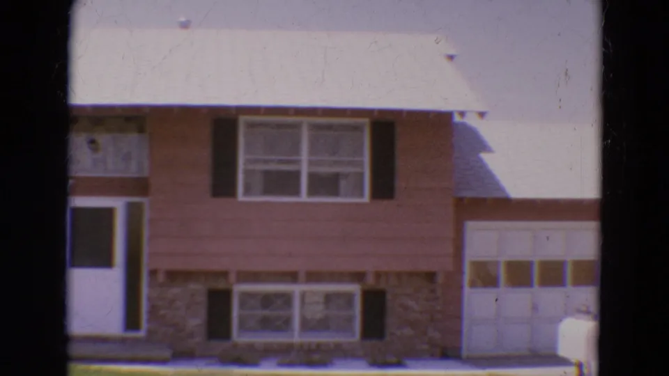 1968 Diller, Nebraska home-movie frame showing the house exterior with its attached white garage door visible on the right.