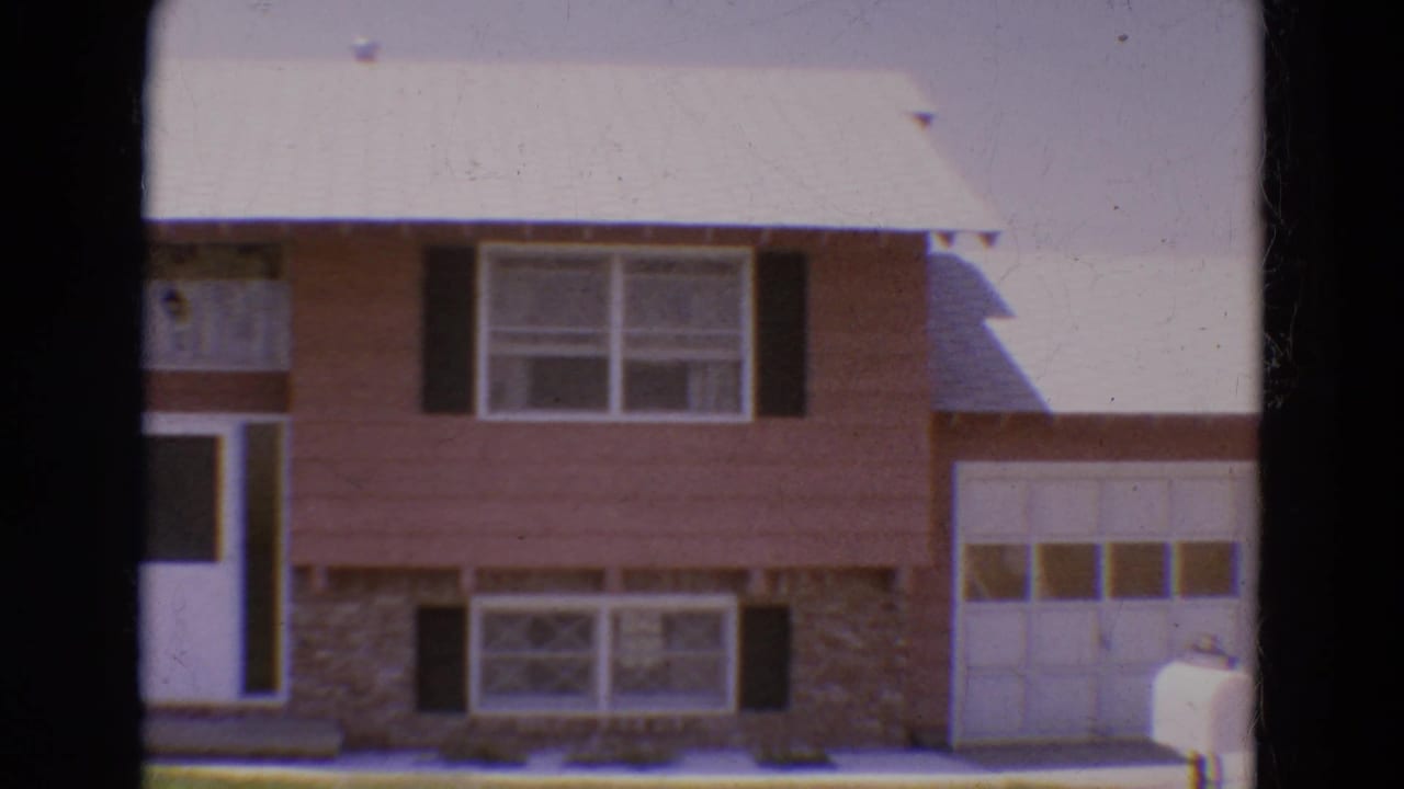 1968 Diller, Nebraska 8mm frame showing a pinkish-brown split-level house with stone facing, dark shutters, garage door, and white mailbox.