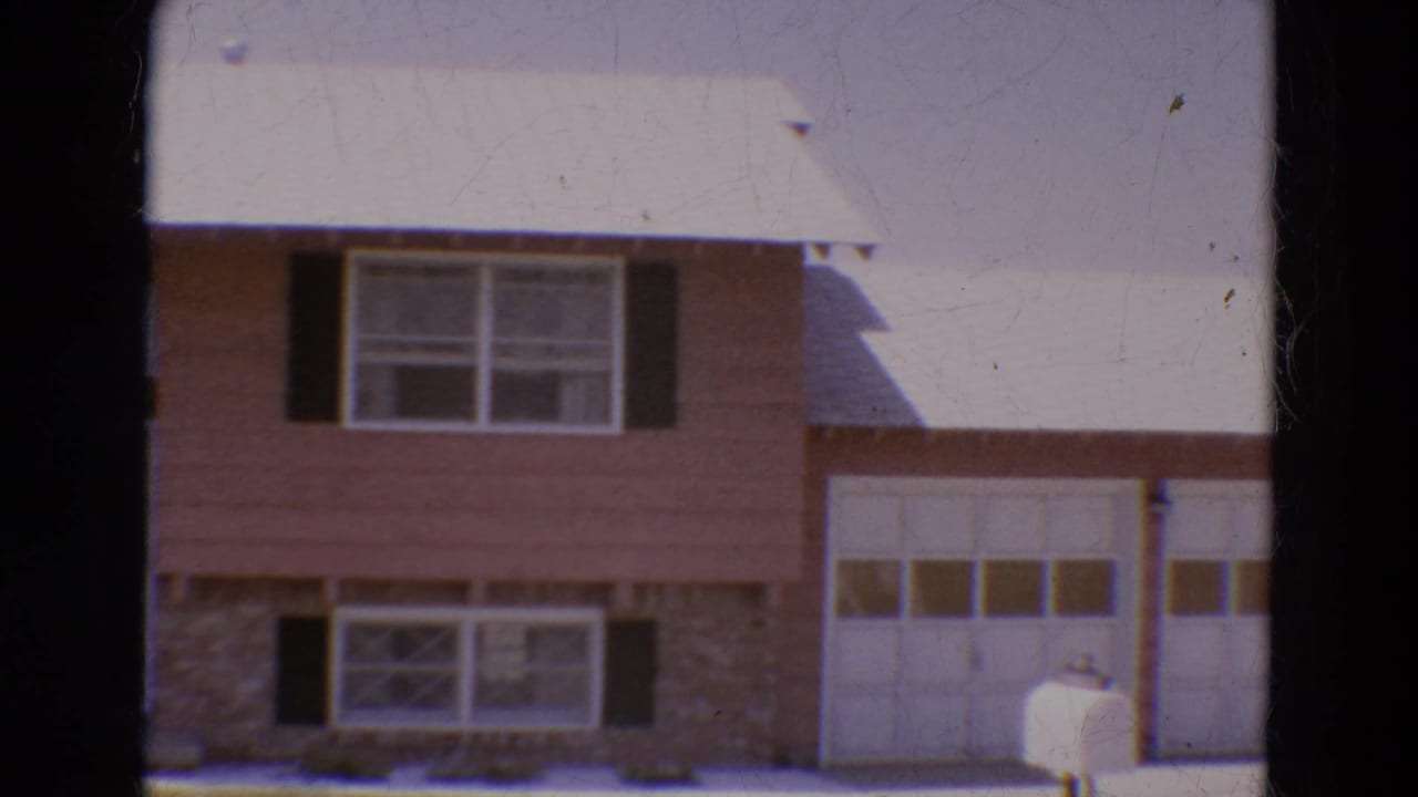 House exterior centered on upper windows, stone lower wall, garage door, and white mailbox.