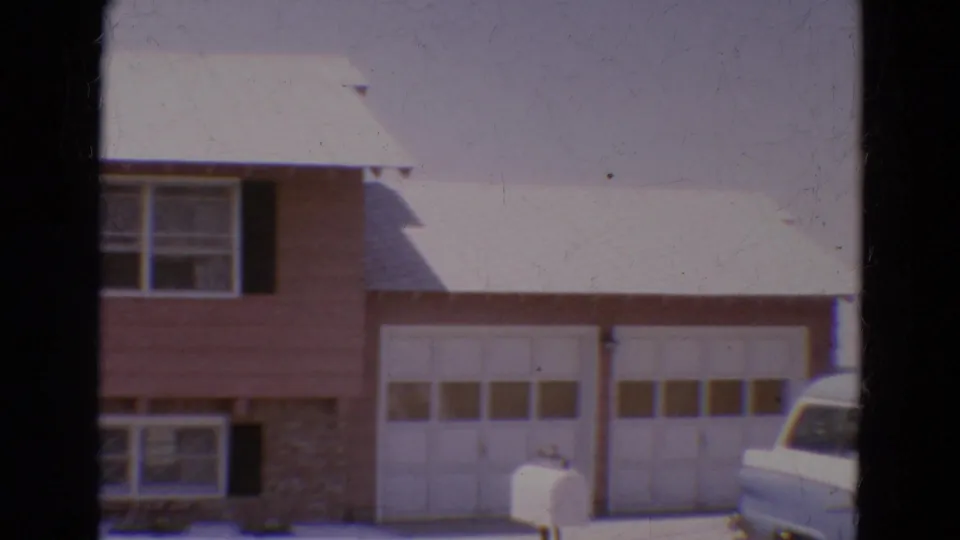 1968 Diller, Nebraska frame showing the right side of the house with twin garage doors, a white mailbox, and part of a car.