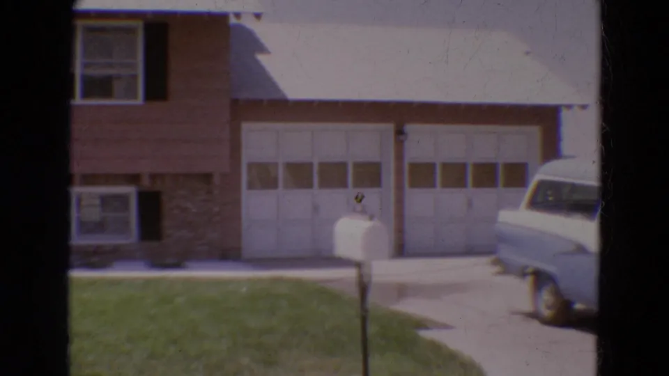 1968 Diller, Nebraska exterior view of a suburban home with a double garage, front lawn, white mailbox, and light station wagon in the driveway.