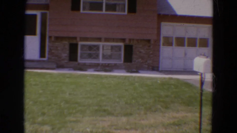 1968 Diller, Nebraska frame showing the front of a suburban house with green lawn, white mailbox, garage door, windows, and entry area.