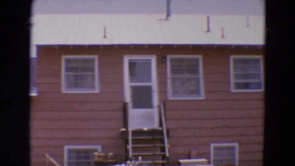 1968 Diller, Nebraska frame of a modest brown house facade with white-trimmed windows, screen door, and entry stairs.