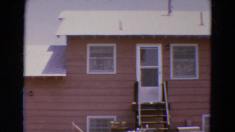 1968 Diller, Nebraska frame with the camera shifted across the brown house, showing the roof edge, door, windows, and lower exterior.