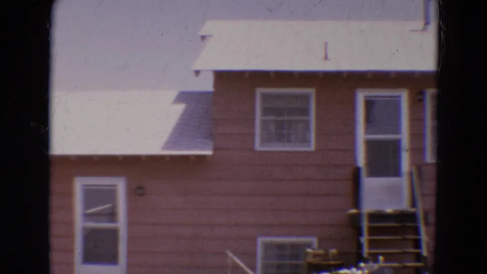 1968 Diller, Nebraska home-movie frame showing a partial brown house facade with white door, steps, windows, and pale roofline.