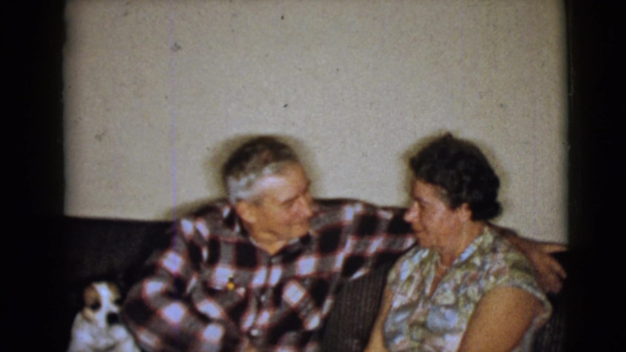 1968 home-movie frame from Clarksdale, Arizona, showing an elderly couple on a couch with a small dog at the left edge.