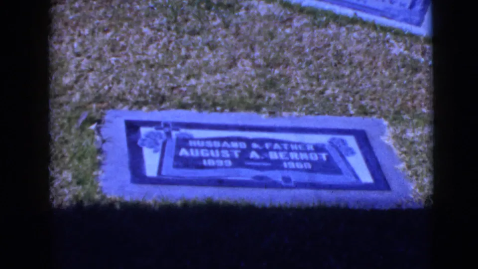 Blue-tinted 1968 8mm frame showing the August A. Berndt grave marker set flush in a grassy cemetery lawn.