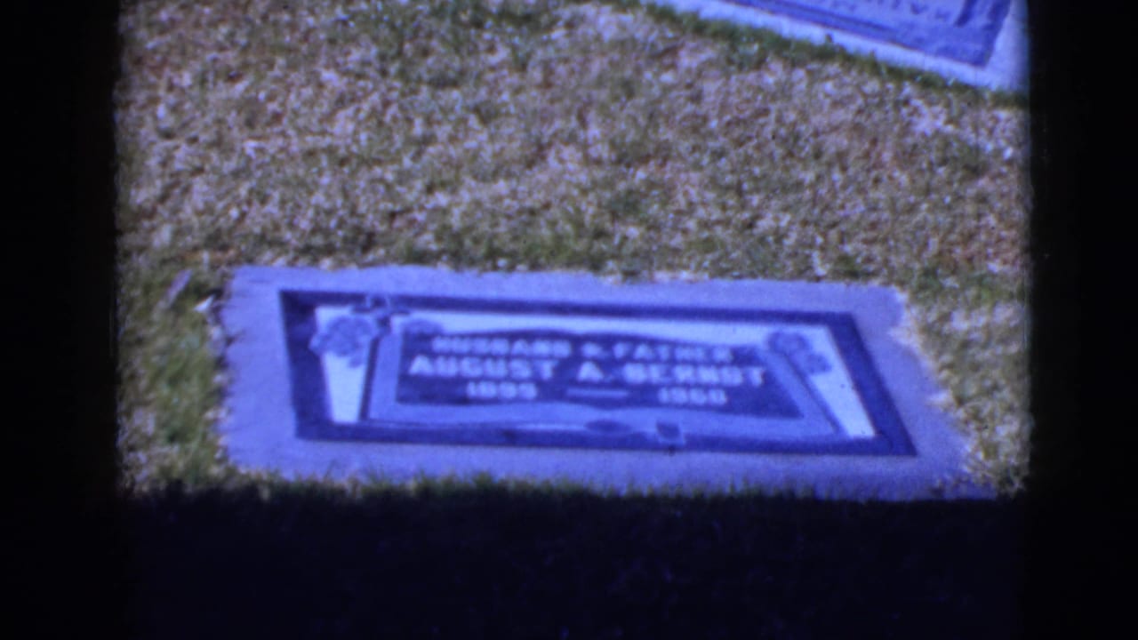Close 8mm frame of the August A. Bernot grave marker in grass, supported by supplied 1968 Clarksdale, Arizona metadata.