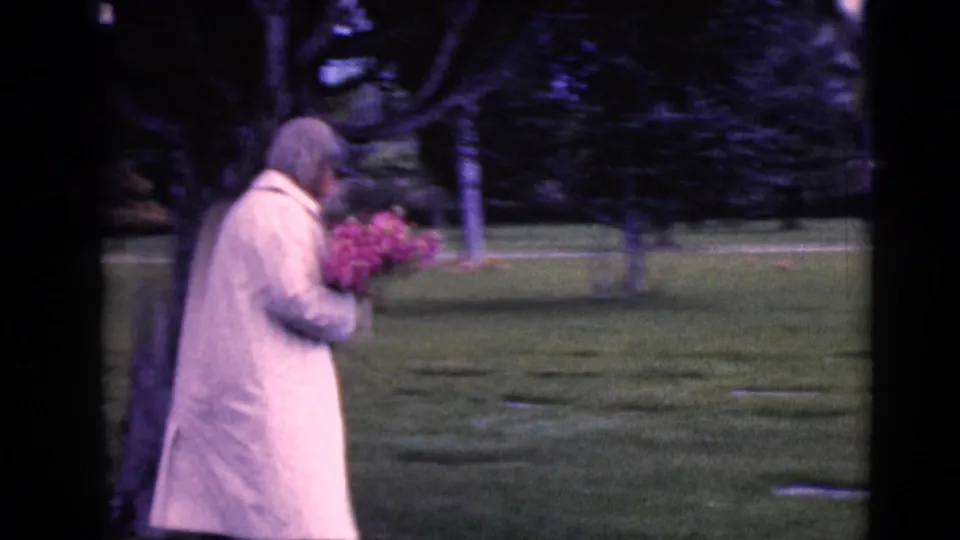 Side-view frame from the 1968 Clarksdale, Arizona clip shows the woman carrying flowers through the cemetery.