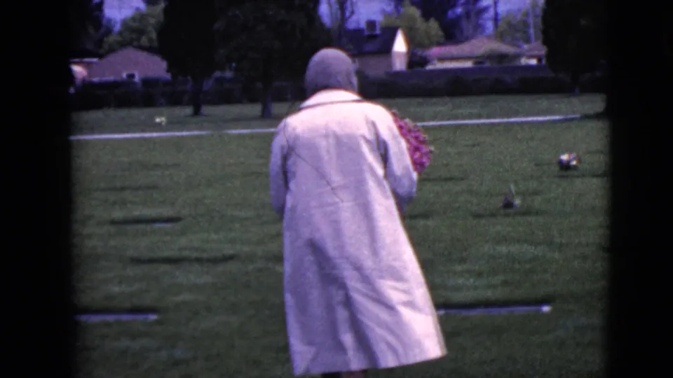 The final frame shows the woman walking away across the cemetery lawn with flowers, framed by aged 8mm film borders.