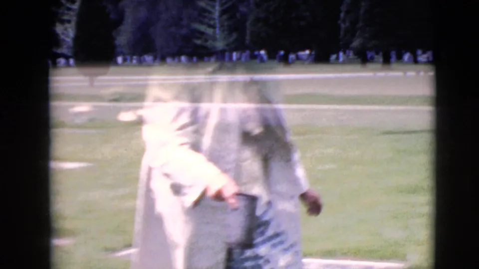 A blurred 1968 home-movie frame shows the elderly woman standing on the Clarksdale cemetery lawn after tending the grave.
