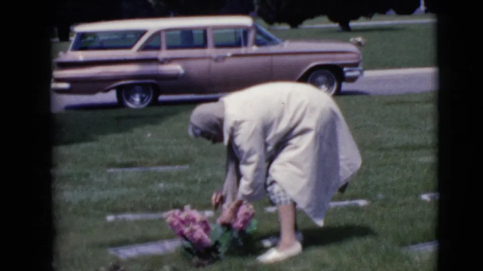The final frame shows the woman bending back toward the pink flowers at the headstone in the Clarksdale cemetery footage.