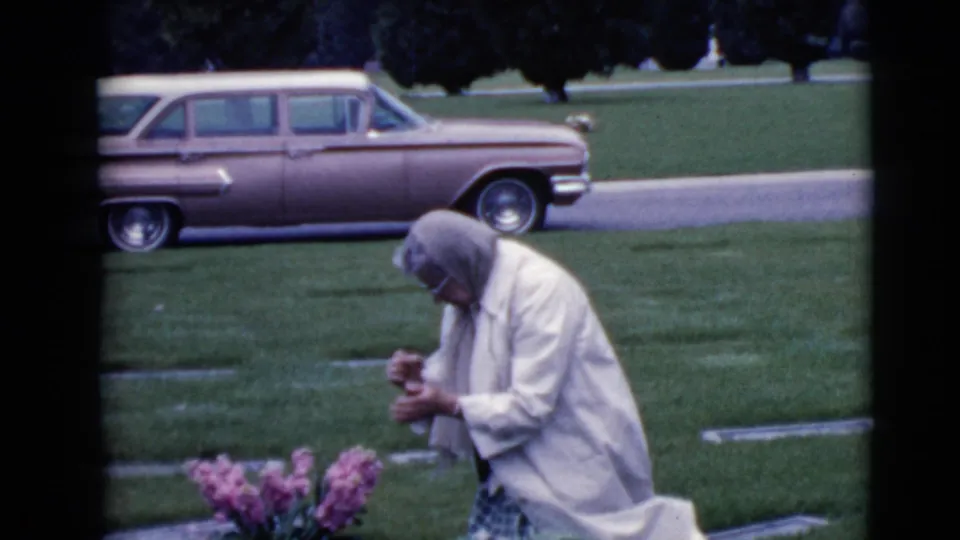 In the final 1968 Clarksdale frame, the woman holds small flowers or stems near the grave, surrounded by lawn markers and a parked station wagon.