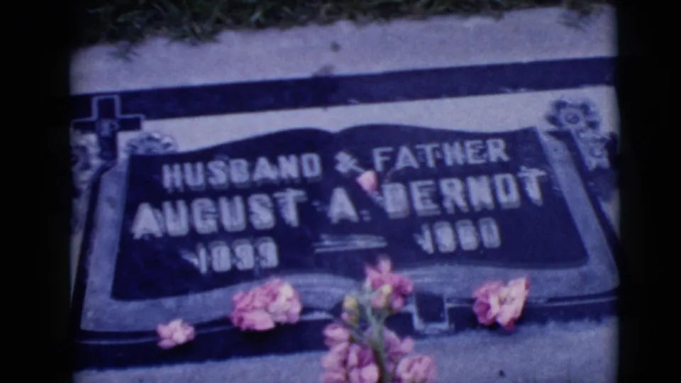 Close-up of a flat cemetery marker for August A. Berndt, marked Husband and Father, with pink flowers placed along the stone.