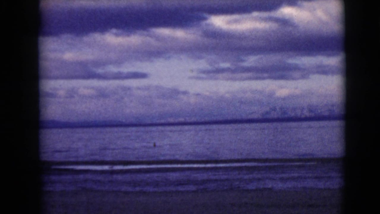 Open water beneath a layered cloudy sky with a distant low horizon.