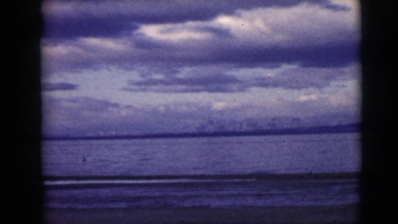 Cloudy sky over calm water with a dark film divider at the left edge.
