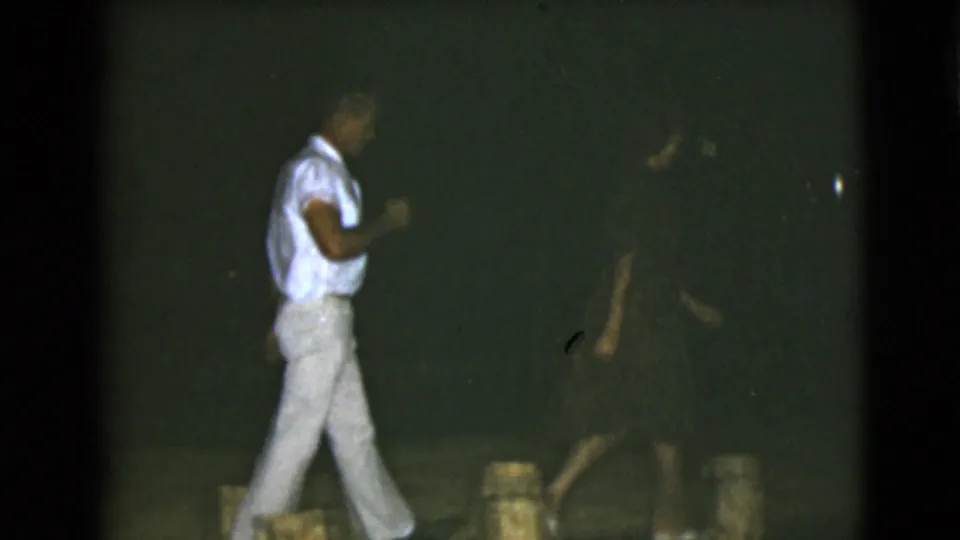 In the Clarksdale, Arizona night footage, the man in light clothing walks across frame as the woman remains partly visible in shadow.
