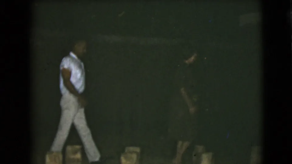 The two men continue across the frame in grainy 1968 Clarksdale, Arizona 8mm footage, with their bodies partly softened by darkness and motion.