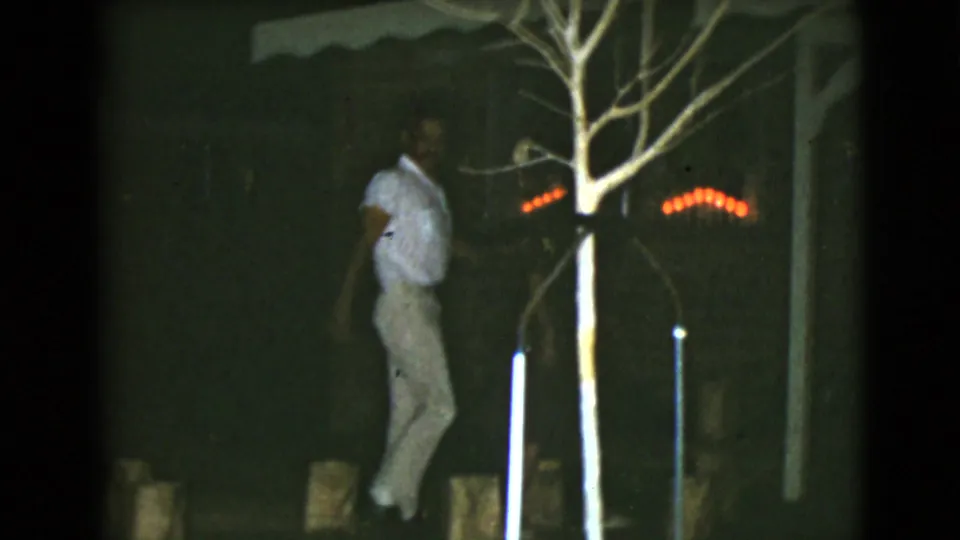 In Clarksdale, Arizona, 1968 home-movie footage, a man in light clothing approaches a brick house entry under red string lights.