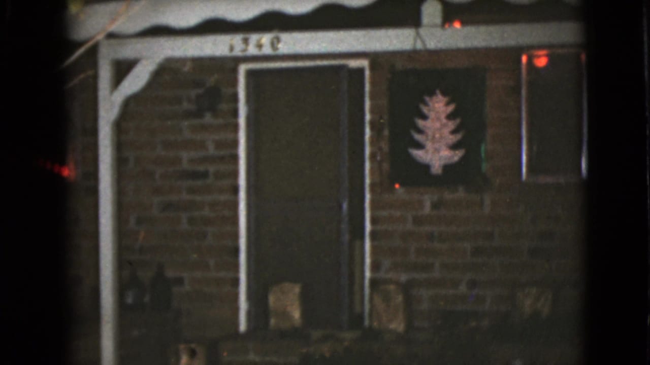 Brick house entry with dark front door, white porch trim, and Christmas wall decoration.