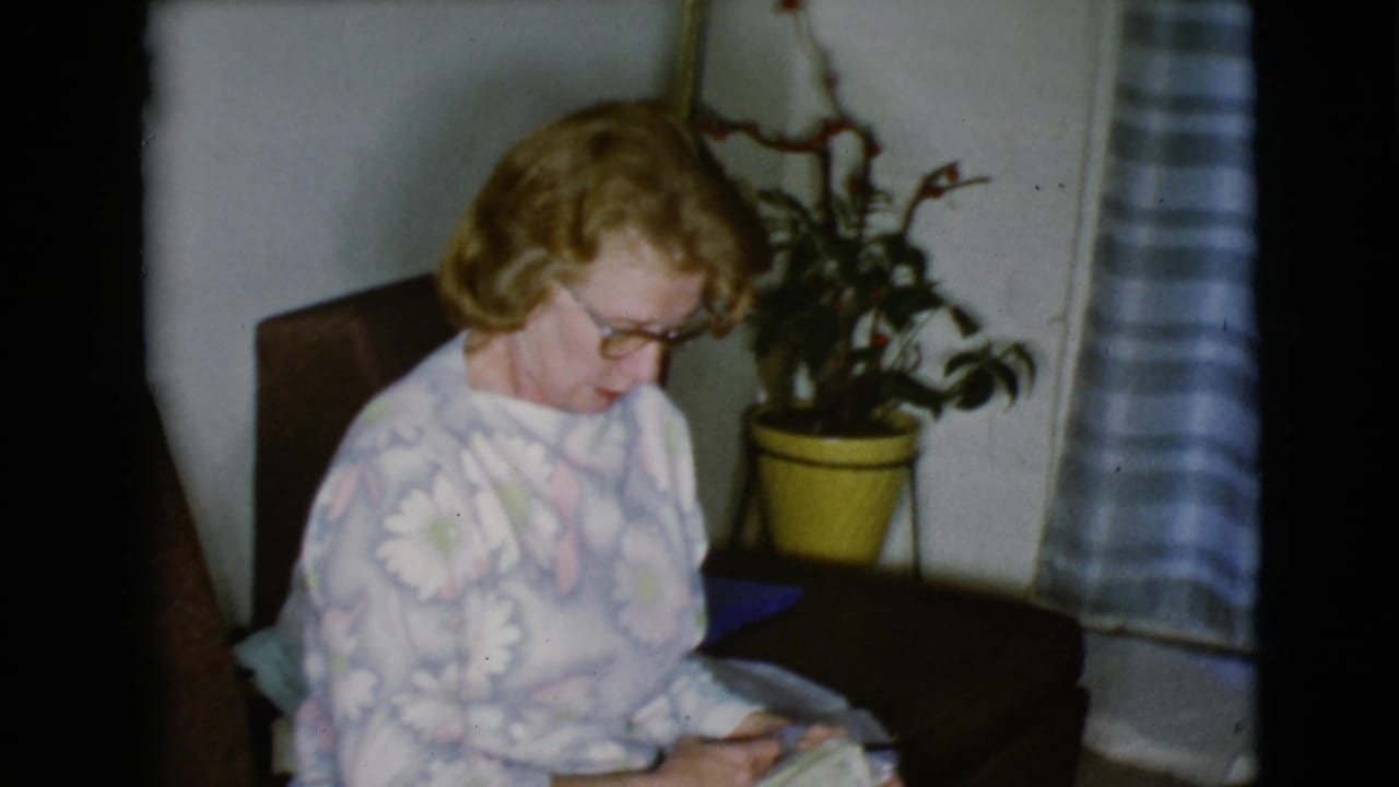 The woman appears focused on a present or object in her lap inside a 1968 Clarksdale, Arizona domestic interior.