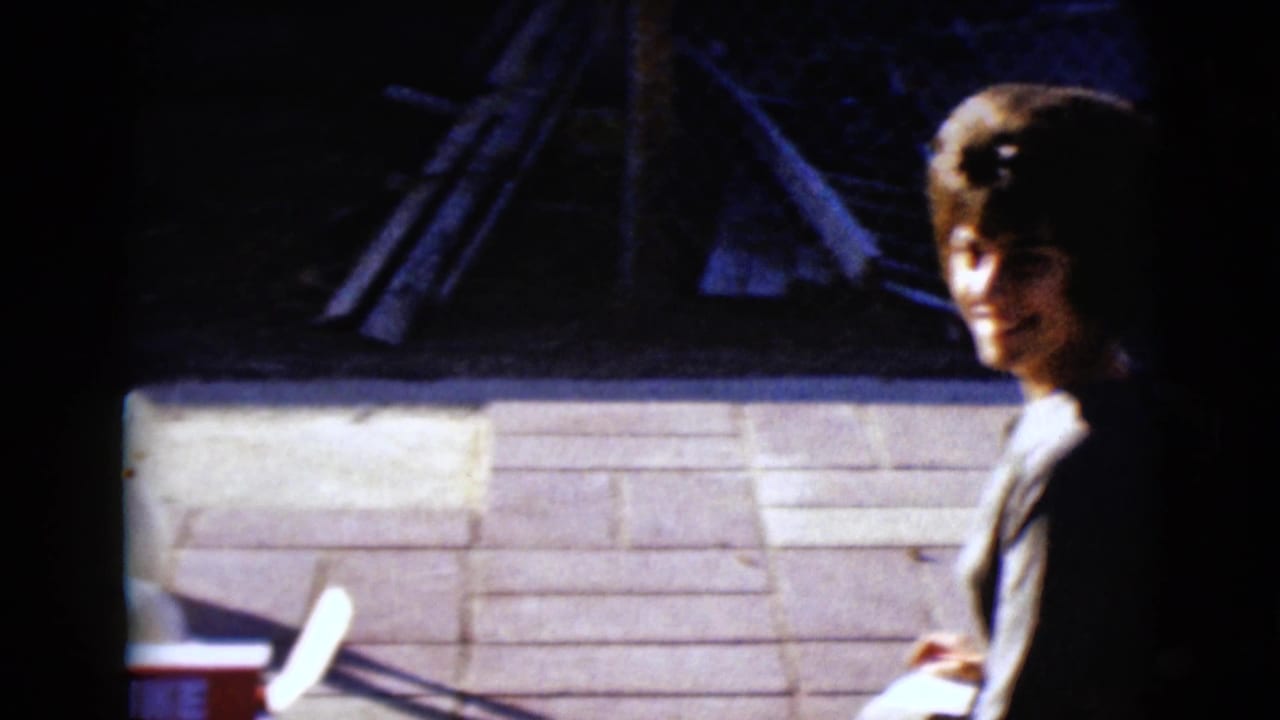 1968 8mm frame from Clarksdale, Arizona showing a woman seated outdoors near a red-and-white mini bowling set box.