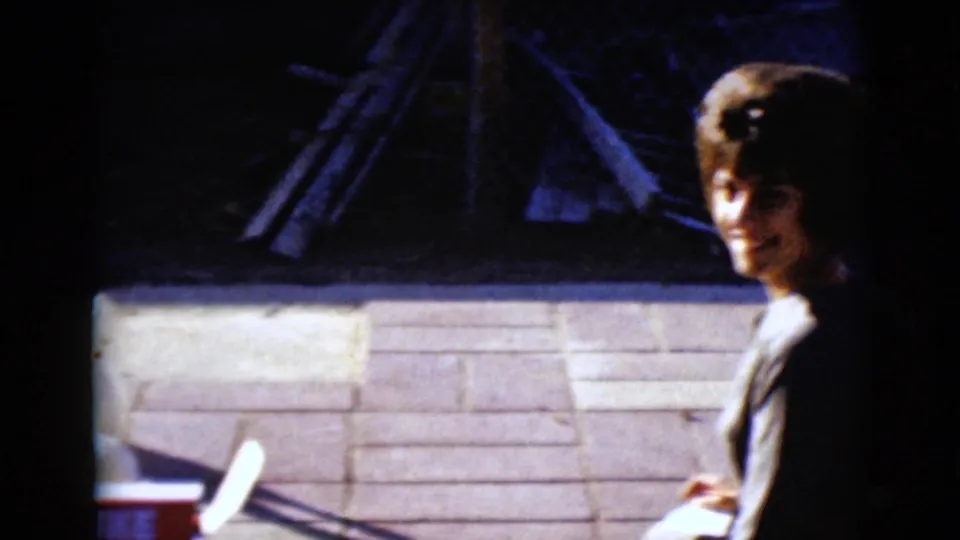 1968 8mm frame from Clarksdale, Arizona showing a woman seated outdoors near a red-and-white mini bowling set box.